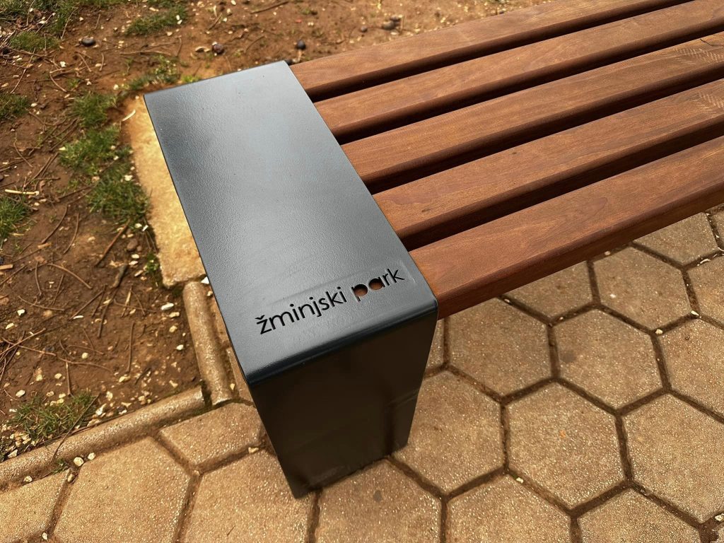 Urezani natpis Žminjski park na čeličnom dijelu klupe
